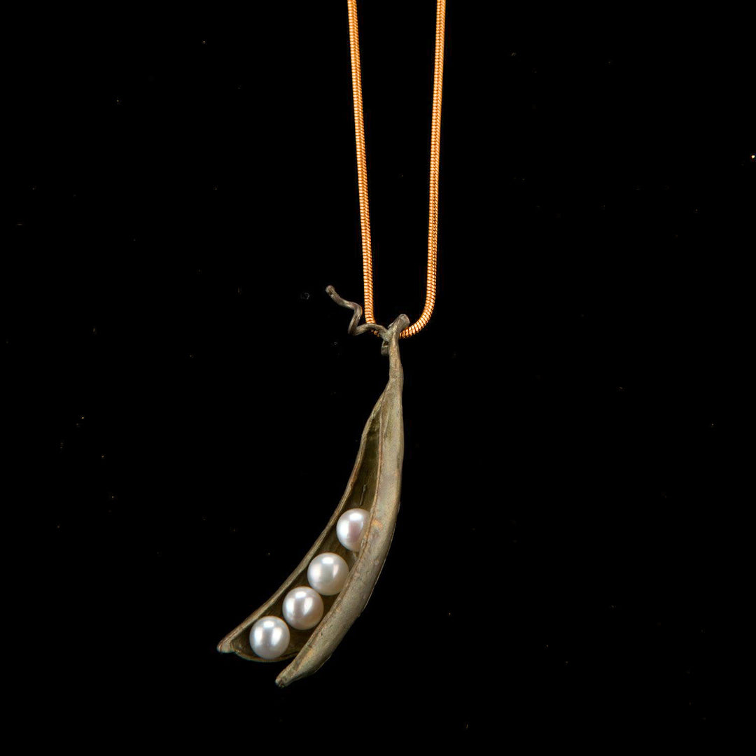 Necklace with a pendant shaped like a pod containing pearls on a black background