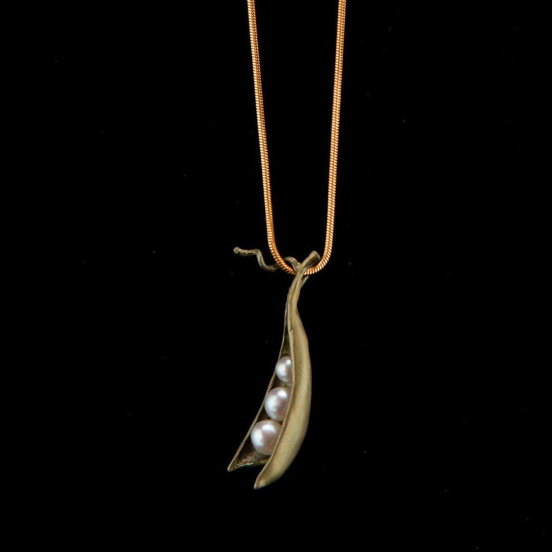 Green pendant shaped like a pod with three pearls on a black background