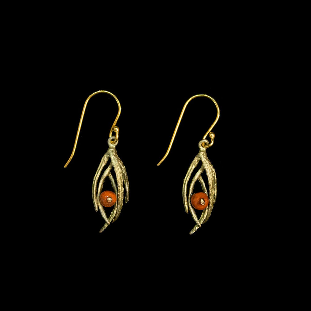 A pair of green leaf drop earrings with a small round orange-red bead at the center, shown against a solid black background.