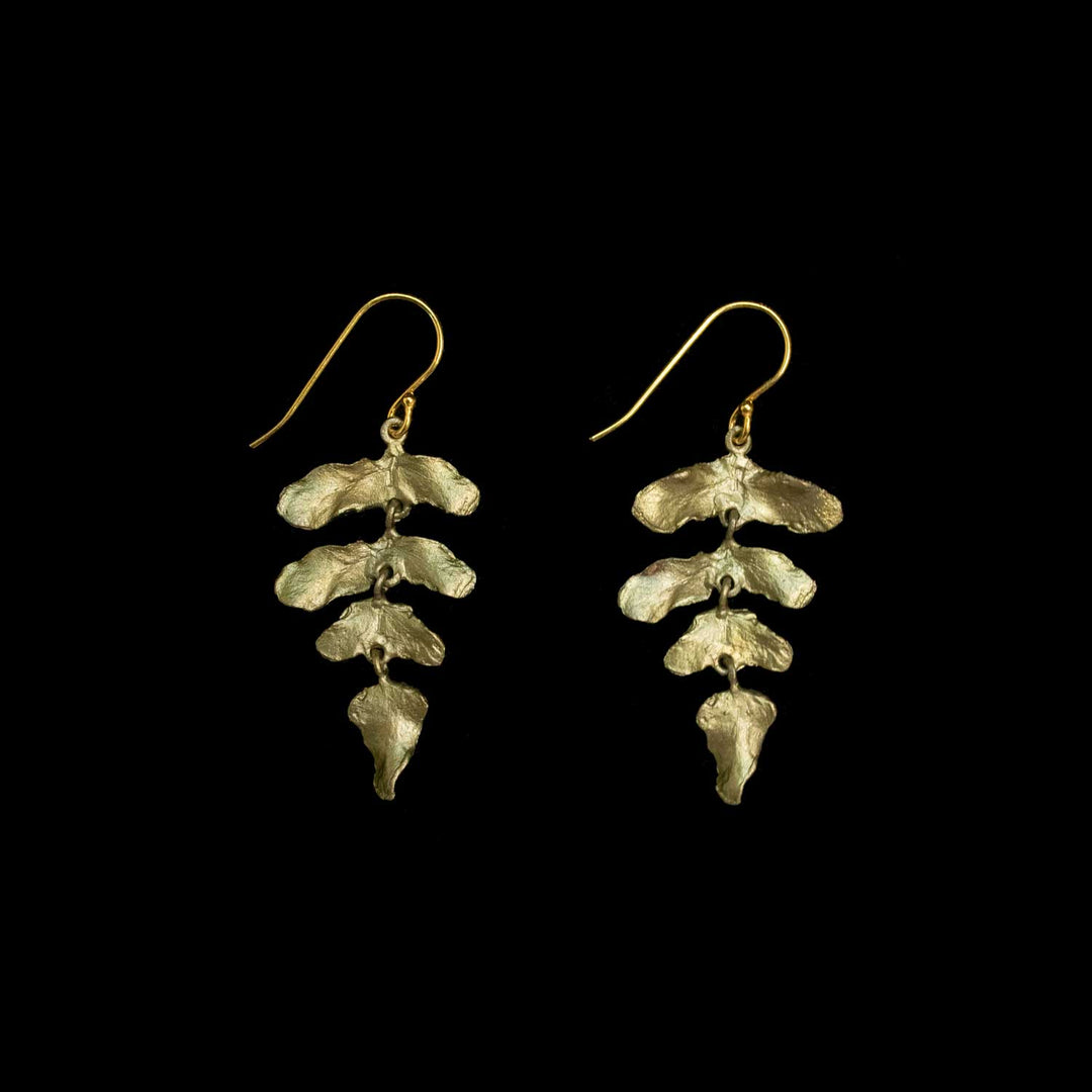 A pair of green dangle earrings with textured, leaf-like organic shapes, shown against a solid black background.