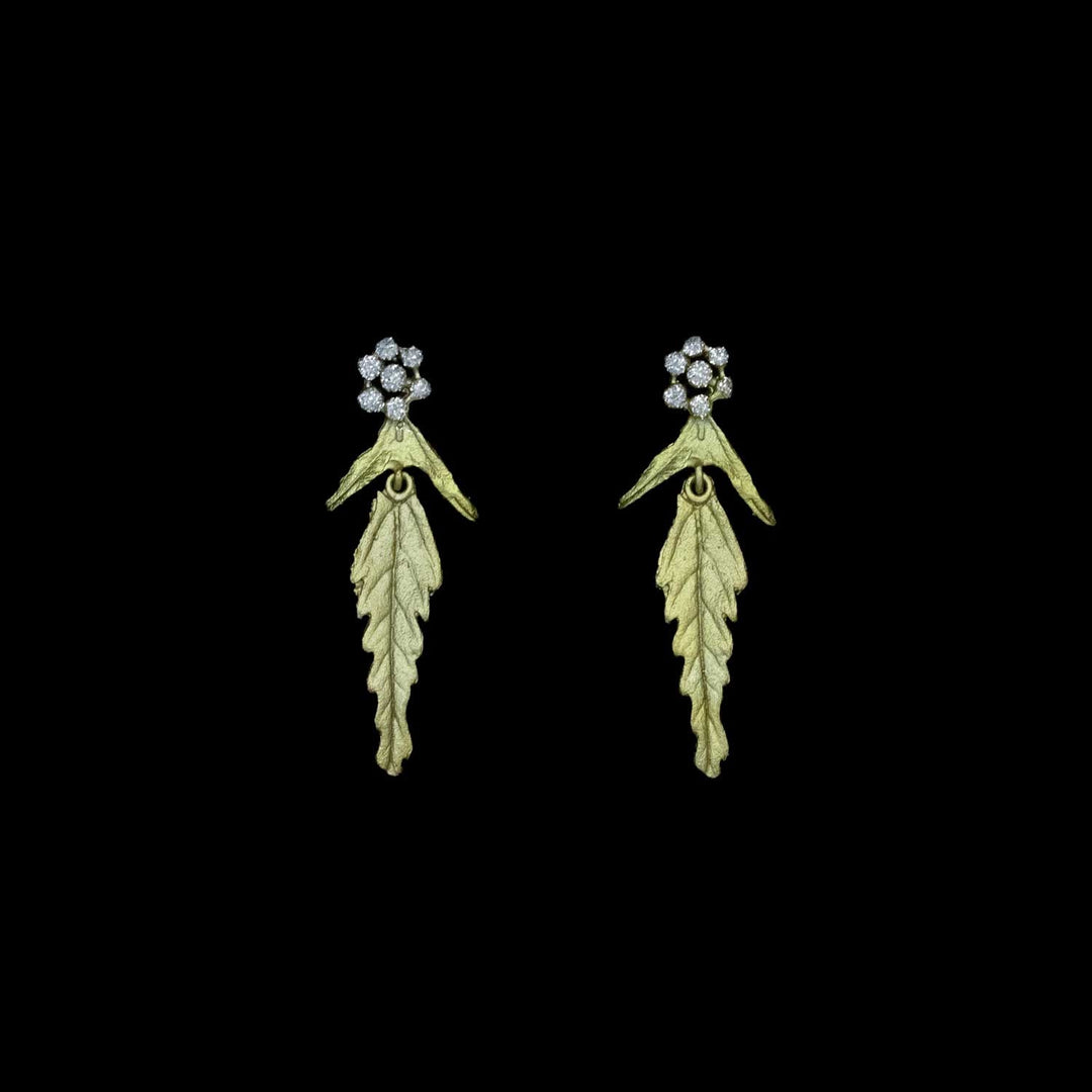 Pair of leaf-shaped earrings with crystal dust clusters at the top on a black background