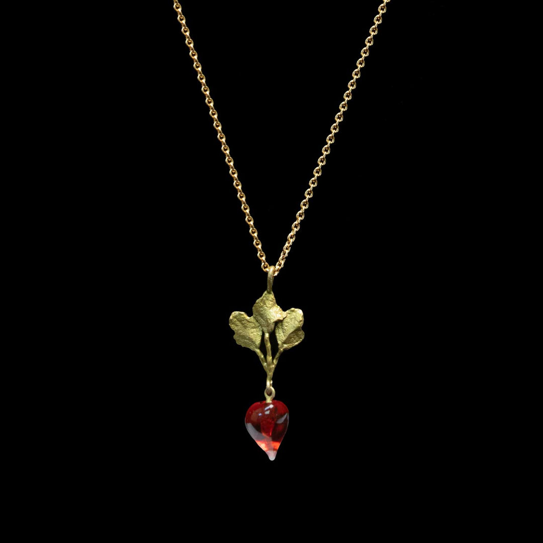 A gold necklace featuring a leaf pendant with a dangling red glass radish, shown against a solid black background.