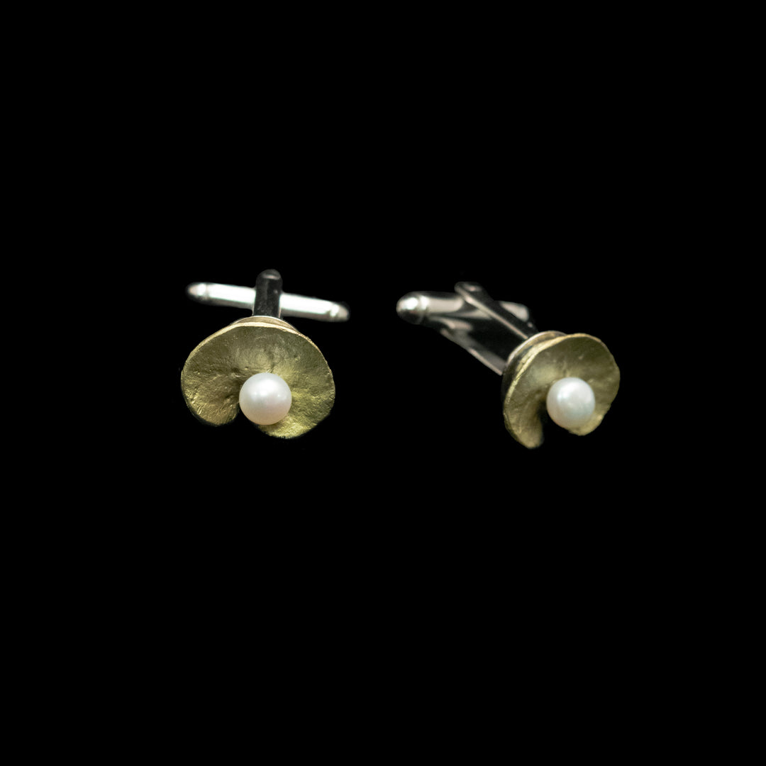 A pair of green and silver cufflinks, each featuring a textured gold crescent shape with a small white pearl at the center, set against a solid black background.
