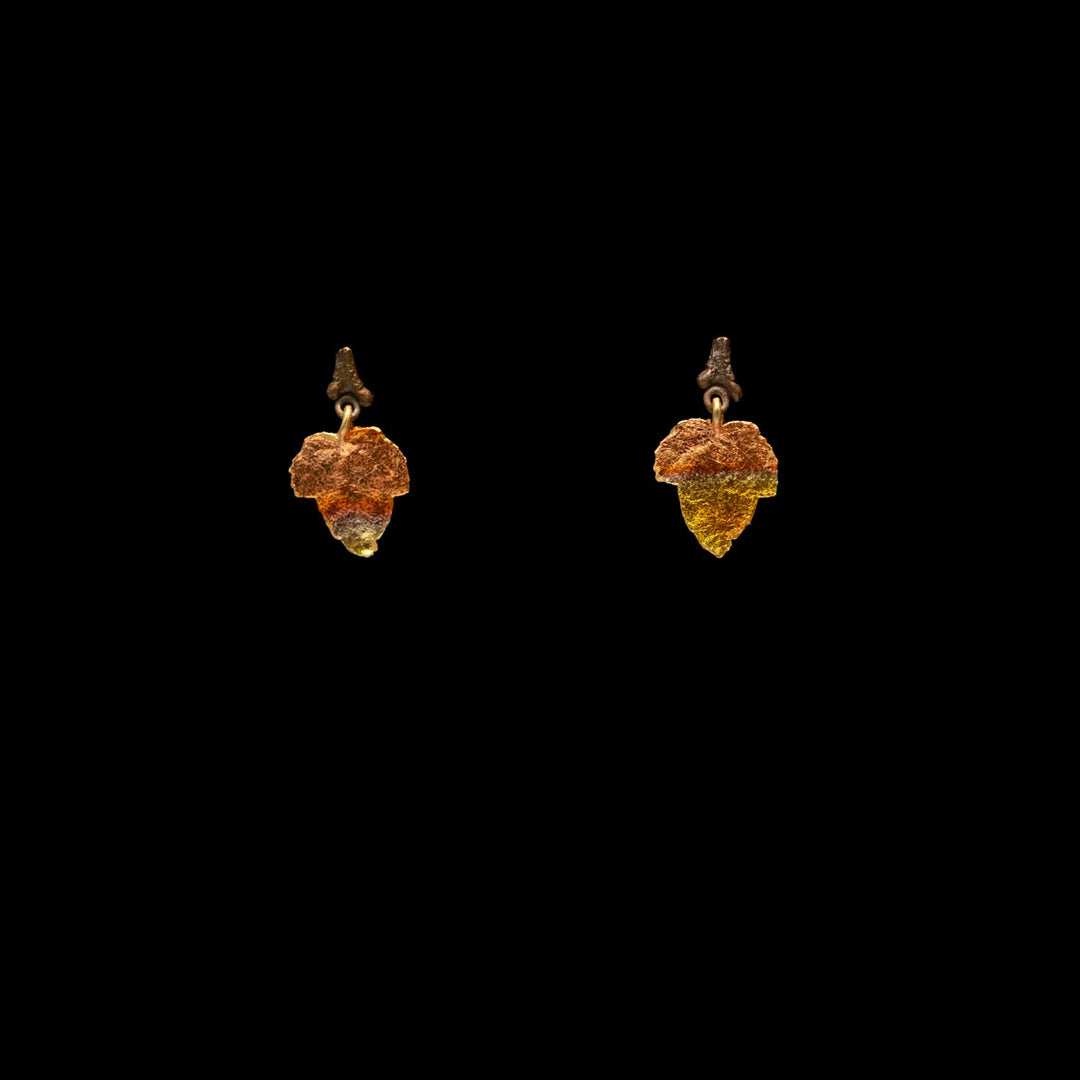 A pair of dangling leaf-shaped earrings with textured brown twigs, shown against a solid black background.