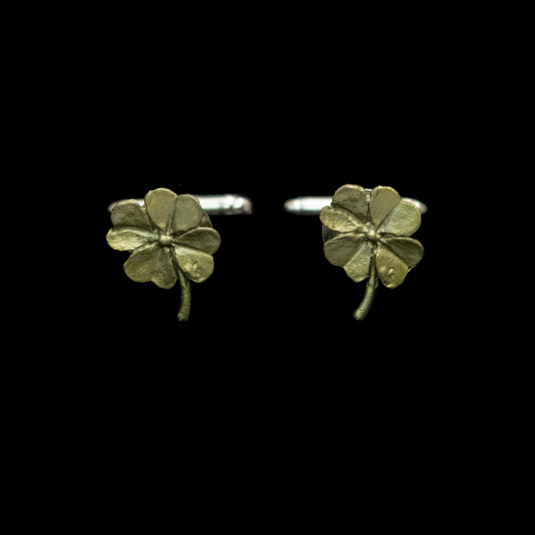 A pair of small four-leaf clover cufflinks with a textured metallic finish, shown against a solid black background.